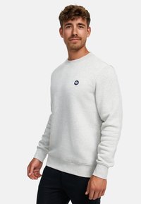 Sudadera gris claro hecha de una tela suave, con cuello redondo, puños acanalados y un pequeño detalle de logo en azul marino en el pecho.