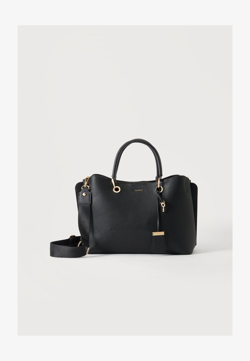 Sac à main en cuir noir texturé avec ferrures dorées, deux poignées, une bandoulière amovible et un petit porte-clés en forme de clé sur un fond clair.