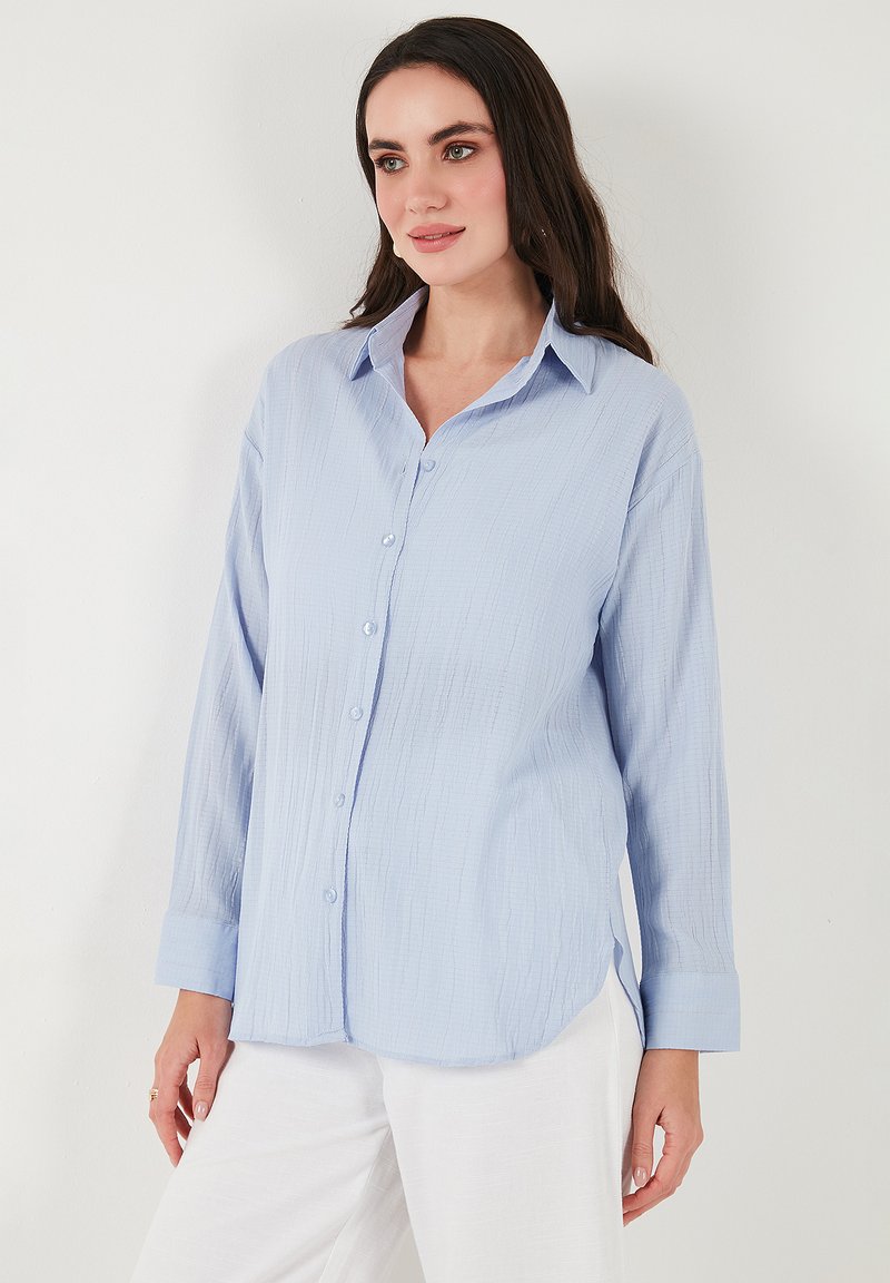 Lichtblauwe button-up shirt van een textuurstof, met lange mouwen en een klassieke kraag. Heeft een rechte snit en zijsplitten voor extra bewegingsvrijheid.
