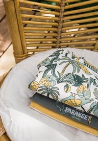 Przedmioty materiałowe ułożone na poduszce: liściasty wzór w zielonym i żółtym, szara warstwa podstawowa i musztardowa warstwa dolna, z widocznymi detalami szycia.