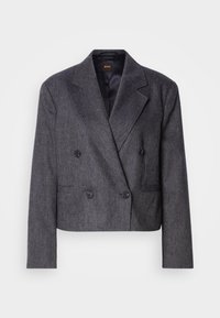 Blazer femme gris foncé à double boutonnage avec revers crantés, quatre boutons, manches longues et poches avant passepoilées.