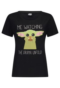 Czarny bawełniany t-shirt z postacią kreskówkową o zielonej skórze i dużych uszach, trzymającą kubek, z napisem "JA OBSERWUJĘ, JAK ROZWINĄ SIĘ DRAMATY".