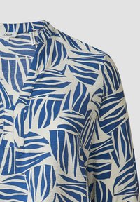 Blauwe en witte blouse met een bladerenpatroon, gemaakt van lichtgewicht stof, met een V-halslijn en een knoopsluiting aan de voorkant.