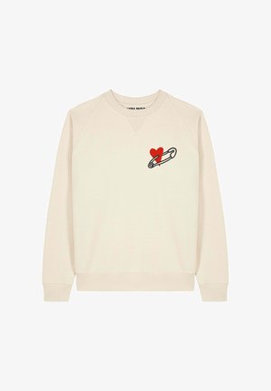 Crème-kleurige sweatshirt met een ronde hals. Heeft een rood hart en safety pin graphic op de linkermouw. Zachte stof, geribde manchetten.
