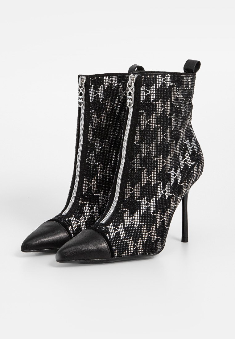 Botines de tacón en blanco y negro con parte superior texturada y brillante, que presentan un patrón de pata de gallo, puntera afilada y cierre de cremallera.