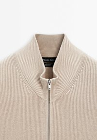 Beiger Baumwollpullover mit Reißverschluss, hohem Kragen, Rippstruktur und silbernem Reißverschluss. Etikett innen mit der Aufschrift "Massimo Dutti".