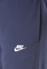 Mörkblå sweatpants i mjuk bomullsblandning. Har en vit Nike-logga på framsidan och sidofickor för förvaring.