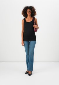 Top negro sin mangas, ajustado, con cuello redondo. Combinado con jeans acampanados de color azul claro, zapatos planos negros y un bolso cruzado burdeos. Cabello con textura, gafas.