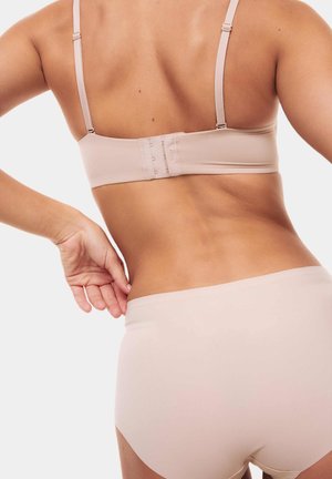 Nude draadloze bh met verstelbare bandjes en haaksluiting; gecombineerd met bijpassende naadloze high-waisted broek in zacht, glad materiaal.