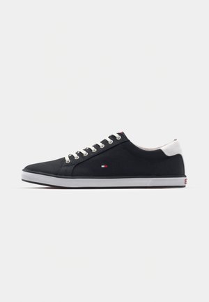 Mørkeblå kanvas sneakers med hvit gummisåle, rund tå og metallhull. Bak på hælen er det et kontrastfarget hvitt panel. Diskret logodetalj.