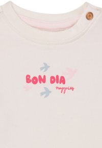 Katoenen t-shirt in crème met een ronde hals. Kenmerkt zich door roze "BON DIA" tekst en blauwe vogel silhouetten. Inclusief een decoratieve knoop op de schouder.