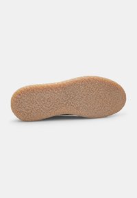 Suela de zapato con una superficie texturada y gomosa de color marrón claro, de forma redondeada y con patrones detallados para mejorar el agarre y la durabilidad.
