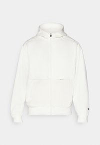 Sweat à zip blanc avec un col haut, des poches avant et des poignets élastiques. Fabriqué en tissu doux avec un léger brillant et sans motifs visibles.