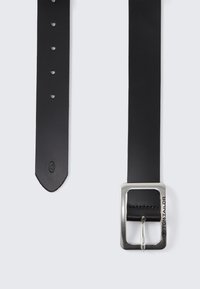 Mustmust mustriba, millel on ristkülikukujuline hõbedane metallist pandla, millel on üks keering ja reguleerimiseks augud. Sile tekstuur ja puhas disain.