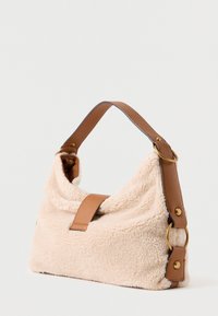 Béžová kabelka z imitace beránka s hnědým koženým popruhem a zlatými kovovými doplňky. Měkká textura, volný tvar a strukturovaný obdélníkový tvar.