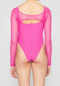 Body a maniche lunghe di un vivace colore rosa, con un tessuto trasparente sulle braccia e un design con schiena scoperta e gamba alta.