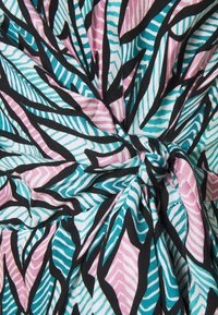 Bunt gemustertes Gewebe mit einem geometrischen Blattmuster in Schwarz, Türkis und Pink. Die Textur ist weich und glatt mit einem geknoteten Detail.