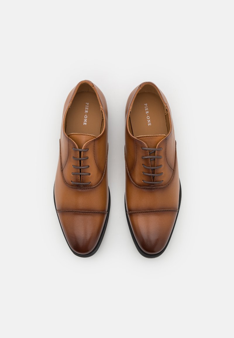 Chaussures de ville en cuir marron avec une texture lisse, à lacets, à bout arrondi et avec de subtils détails de couture. Nom de la marque "PIER ONE" à l'intérieur.