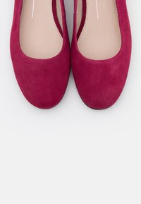 Fuchsia suede ballet flats with a rounded toe and smooth finish. The insoles are beige, and the shoes have a low profile.