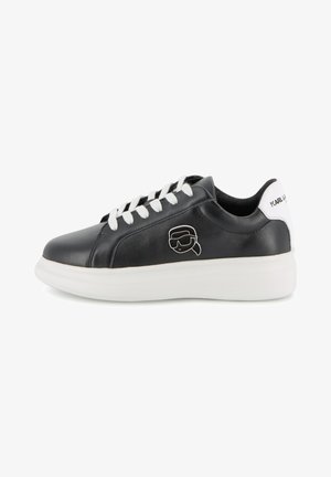 Melns ādas sporta apavs ar baltām auklām un baltu zoli. Sānos ir karikatūras varoņa logotips un teksts papēdī.