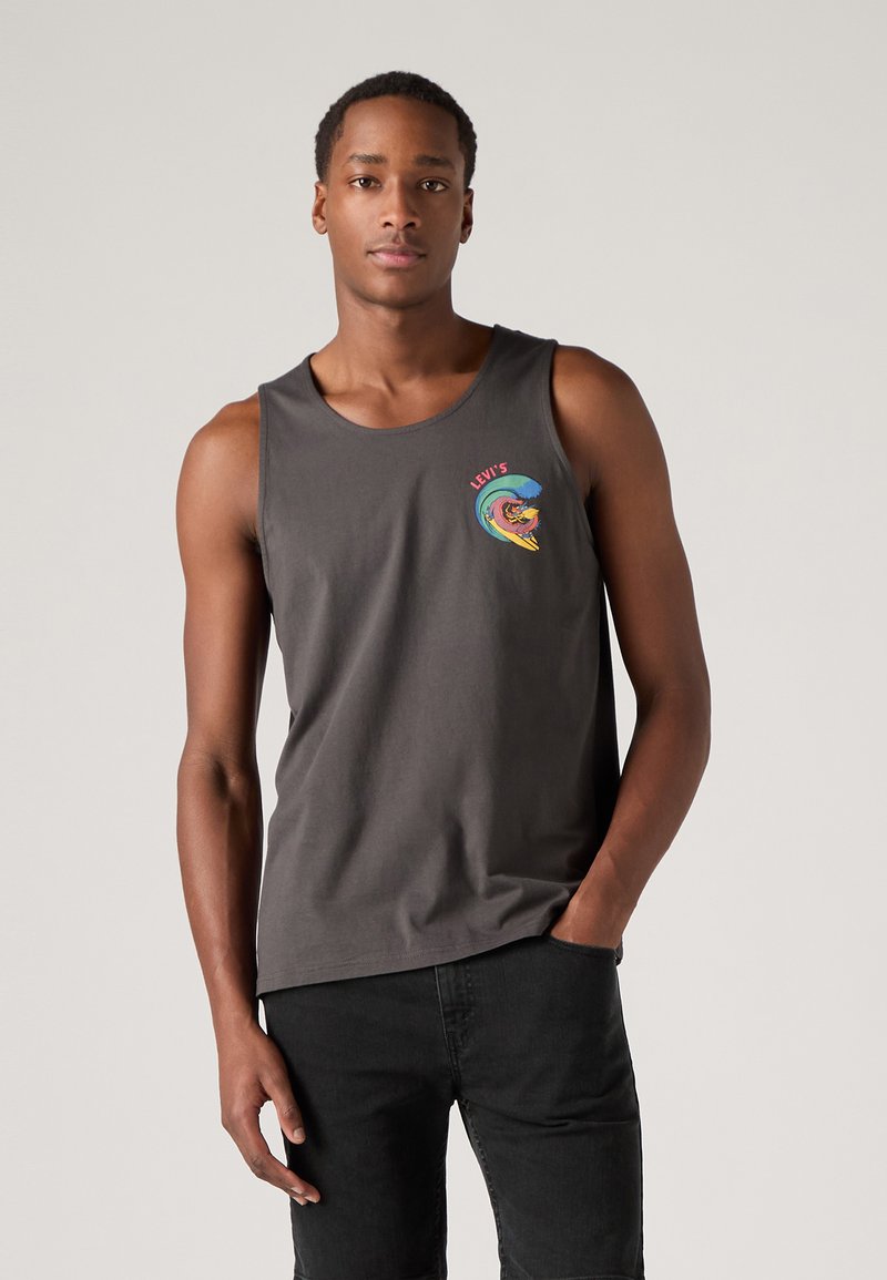 Débardeur en coton gris avec un col rond affichant un design graphique coloré de Levi's sur la poitrine gauche. Porté avec un jean noir.