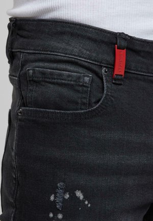 Zwarte denim jeans met een slim fit, vijf zakken, een klein voorkantzakje, versleten details en een rood merketiket op de tailleband.