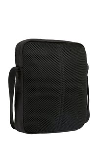 Bolsa negra con un frente de malla texturizada, forma rectangular y correa de hombro ajustable. Presenta un respaldo de tela suave para mayor durabilidad.