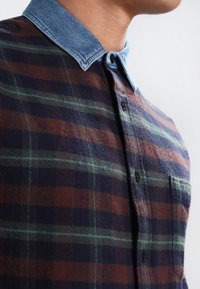 Geruite flanellen shirt met een denim kraag, in marineblauw, rood en groen. Inclusief een zak en knoopsluiting aan de voorkant.