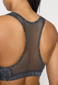 Αθλητικό σουτιέν με γκρι λωρίδα λεοπάρ, πλέγμα στην πλάτη και σχέδιο racerback. Διαθέτει λείο ύφασμα και ελαστικές άκρες για άνεση.