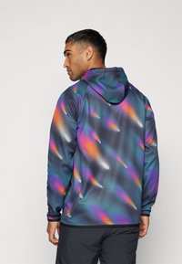 Felpa con cappuccio caratterizzata da uno sfondo scuro con vivaci pattern astratti in viola, arancione e teal; realizzata in un materiale morbido e leggero.