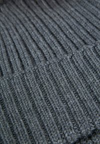 Tessuto a maglia grigio scuro con texture a coste verticali e dettagli di cucitura spessa in vista ravvicinata.