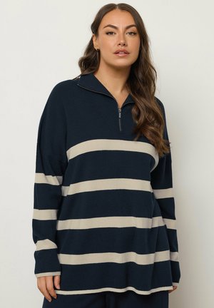 Pullover navy con design a righe crema, dotato di colletto con zip quarti e vestibilità ampia. Il morbido tessuto a maglia offre una texture confortevole.