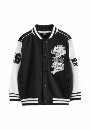 Veste universitaire noir et blanc avec boutons-pression, écusson tigre, texte "New York", numéro 76 sur la manche gauche, et col, poignets et ourlet rayés.