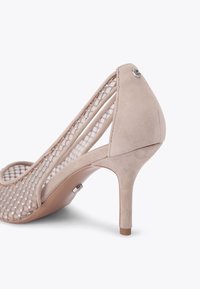 Beżowy but na wysokim obcasie z teksturowanym wykończeniem z zamszu, z siateczkowymi detalami i małym akcentem przy obcasie. Wygięty kształt z ostrym noskiem.