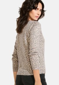 Sweter w panterkę w beżowo-jasnobrązowym kolorze, wykonany z miękkiego dzianiny, z długimi rękawami i dopasowanym krojem.