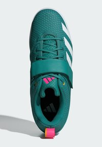 Zelené atletické topánky s priedušnou sieťovinou, biele pruhy, textured povrch, nastaviteľný remienok a ružové a žlté akcenty na päte.