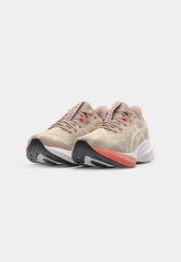 Lichtbeige sportieve schoenen met een gestructureerde bovenkant, roze accenten en een zwarte rubberen zool met witte en oranje details.
