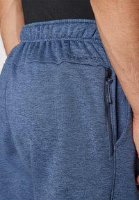 Blå atletiske shorts lavet af struktureret stof, med en elastisk talje, sidelomme med lynlås og prægning af logodetaljer.