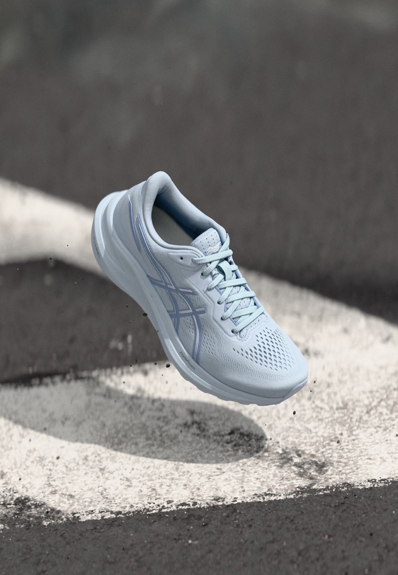 Scarpa da corsa azzurro chiaro con tomaia in rete traspirante, forma liscia e arrotondata, suola testurizzata e dettagli blu sul logo laterale.