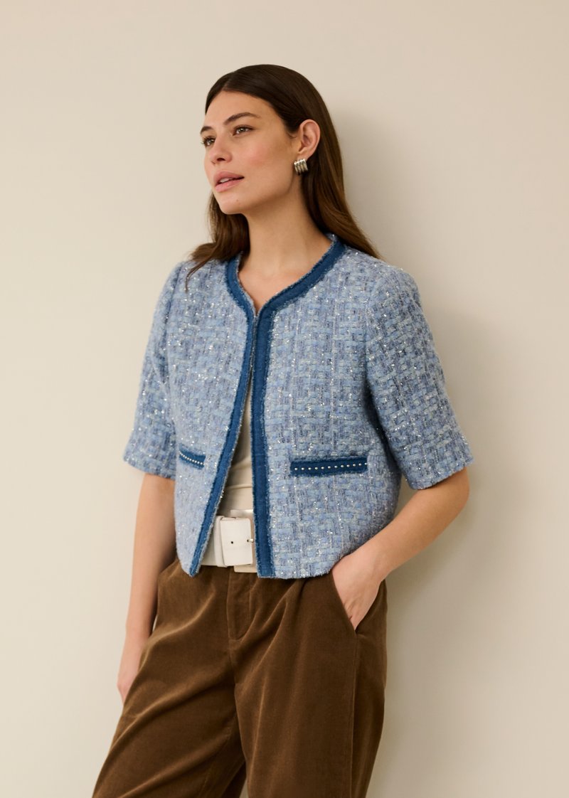 Blaue Tweedjacke mit rundem Ausschnitt, kurzen Ärmeln, blauer Einfassung und Taschen mit dekorativen Akzenten. Strukturierte, kastige Silhouette.
