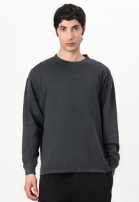 Dark gray long-sleeve t-shirt made of soft cotton, featuring a crew neckline, relaxed fit, and minimal design with no visible logos.