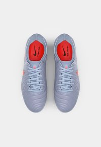 Nike Tiempo soccer shoes, light grey synthetic upper, textured design, red accents on the interior and logo, flat laces, rounded toe.