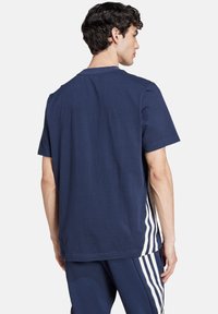 T-shirt in cotone blu navy con maniche corte, caratterizzata da righe verticali bianche sui lati e un classico colletto a girocollo.