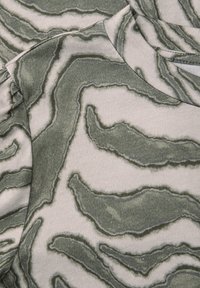 Weicher Stoff mit einem abstrakten wellenförmigen Muster in Grautönen und Weiß, mit einem runden Ausschnitt und überlappenden Lagen.