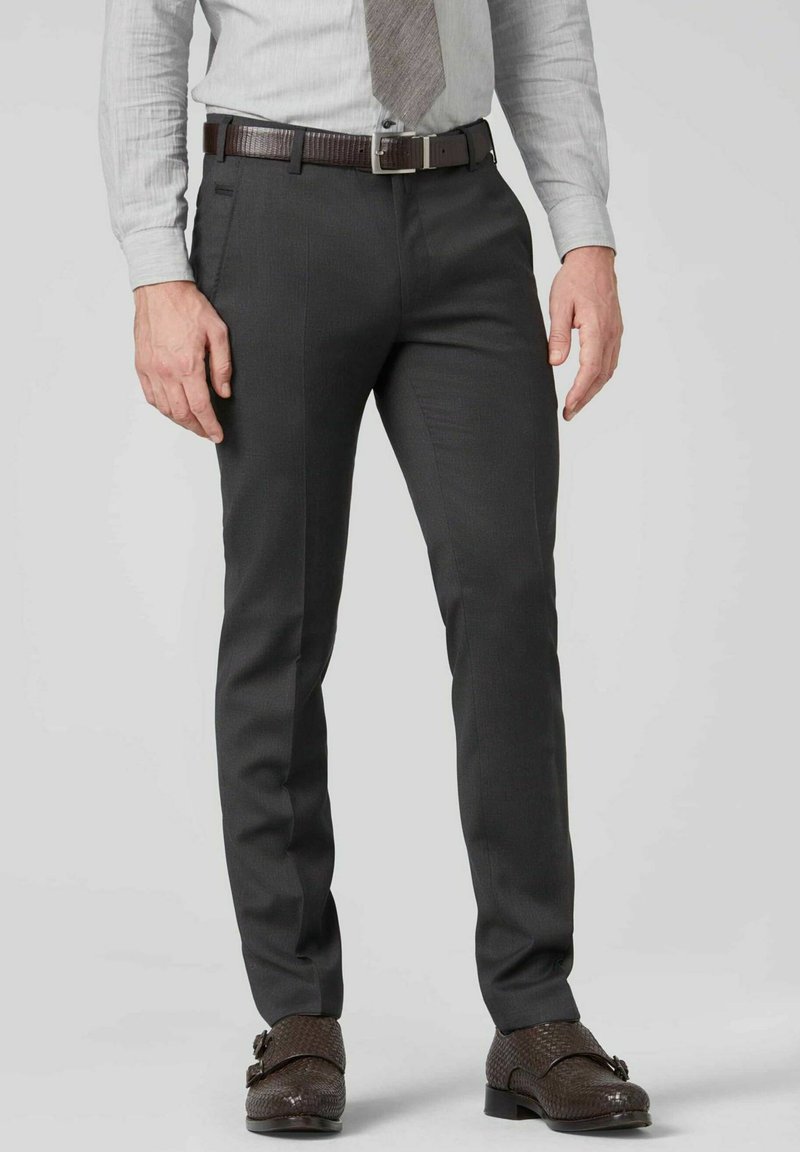 Pantalon ajusté gris en matière lisse, avec une coupe droite, des poches avant et un léger brillant. Associé à une cravate à motifs et des chaussures.