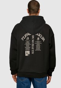 Schwarze Kapuzenjacke mit einem großen Grafikdruck auf dem Rücken, der Songtitel und ein Foto zeigt. Hergestellt aus weichem Stoff mit einer lockeren Passform.