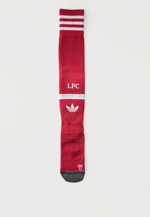 Czerwona sportowa skarpeta z białymi paskami, tekstem „"LFC"”, logo Adidas oraz szarą częścią na palcach, ułożona płasko na białym tle.