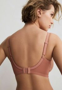 Roze beha met verstelbare banden, zachte textuur en een haak-en-oogsluiting aan de achterkant. Gladde naden en minimale ontwerpelementen.