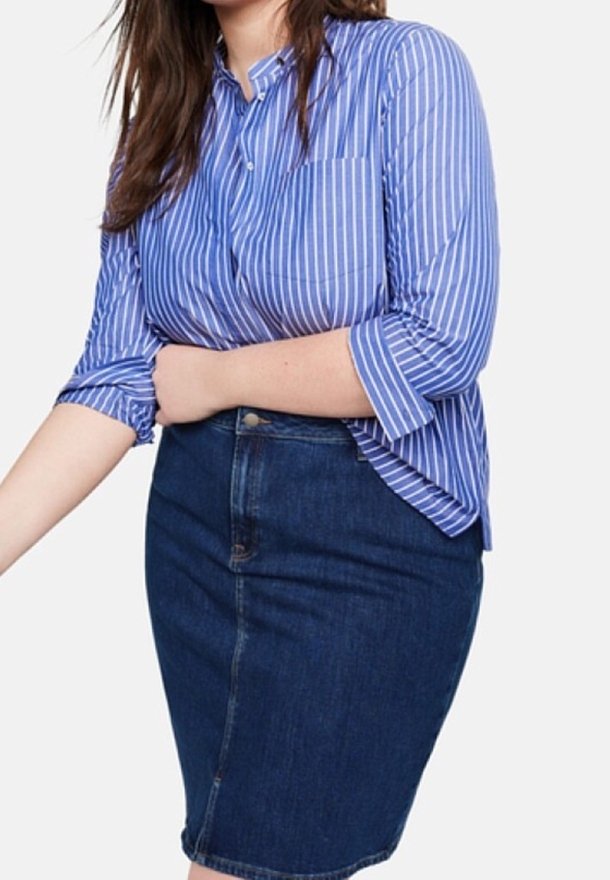 Camisa de botones a rayas azules y blancas con mangas remangadas, combinada con una falda lápiz de mezclilla oscura. Texturas suaves y diseño ajustado.