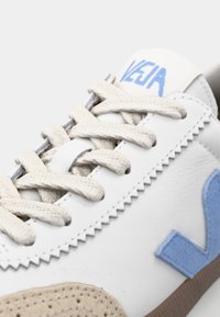 Sneaker in pelle bianca con accenti in suede beige, logo azzurro chiaro e lacci beige. Caratterizzato da cuciture decorative e sovrapposizioni testurizzate.
